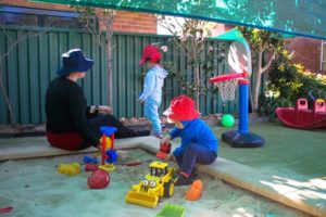 Beverly Montessori teacher and kids in sandbox
